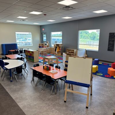 An easel, interactive tables, and colorful seating invite young children to the Foundations Community Childcare Center