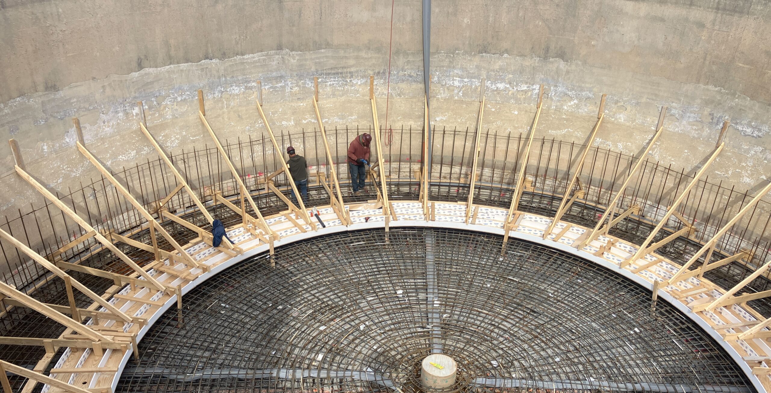 Two construction employees are preparing a tank for a concrete pour at a water treatment plant